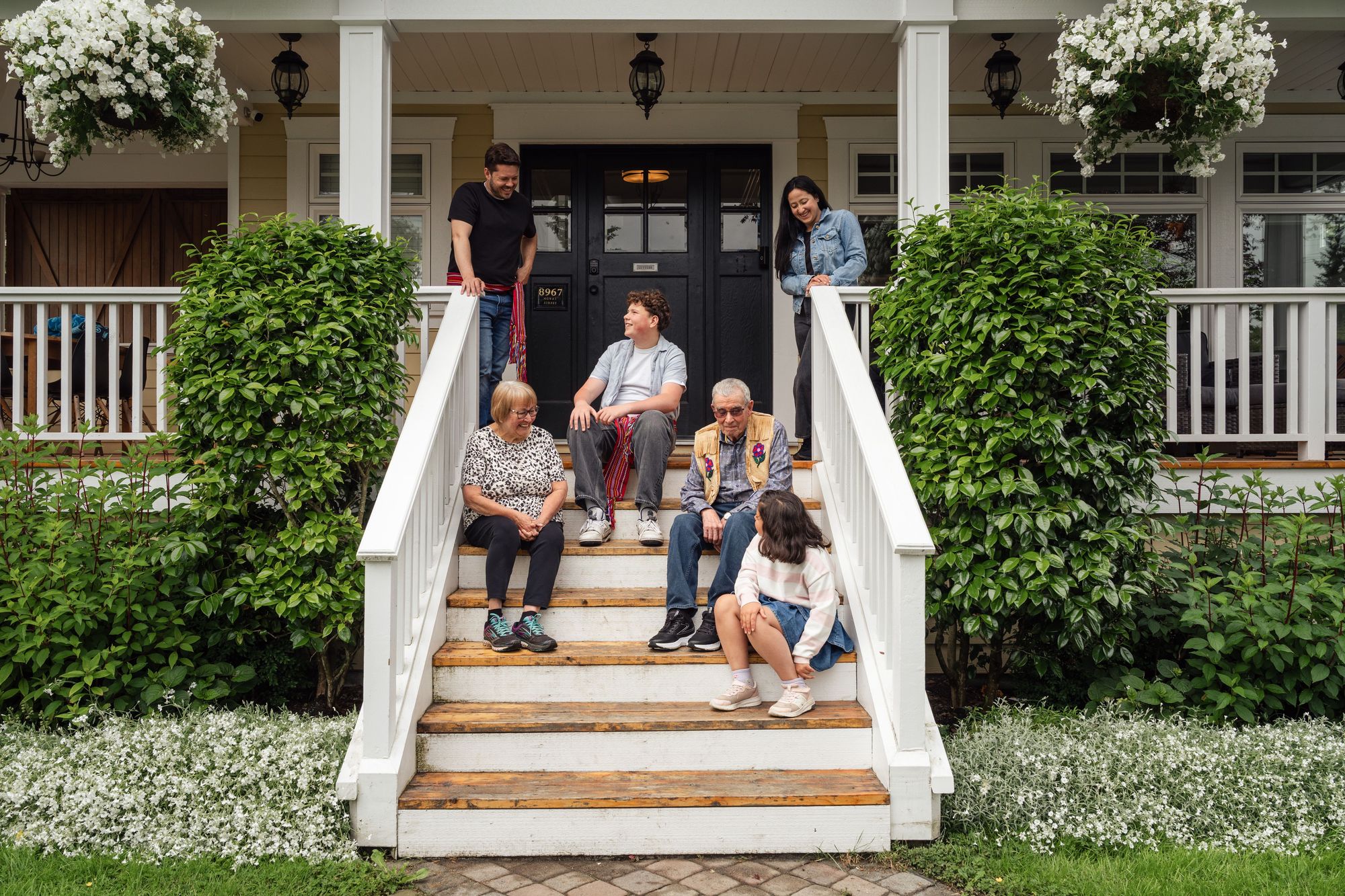 Three generations of a family gathered on the front steps of their home
